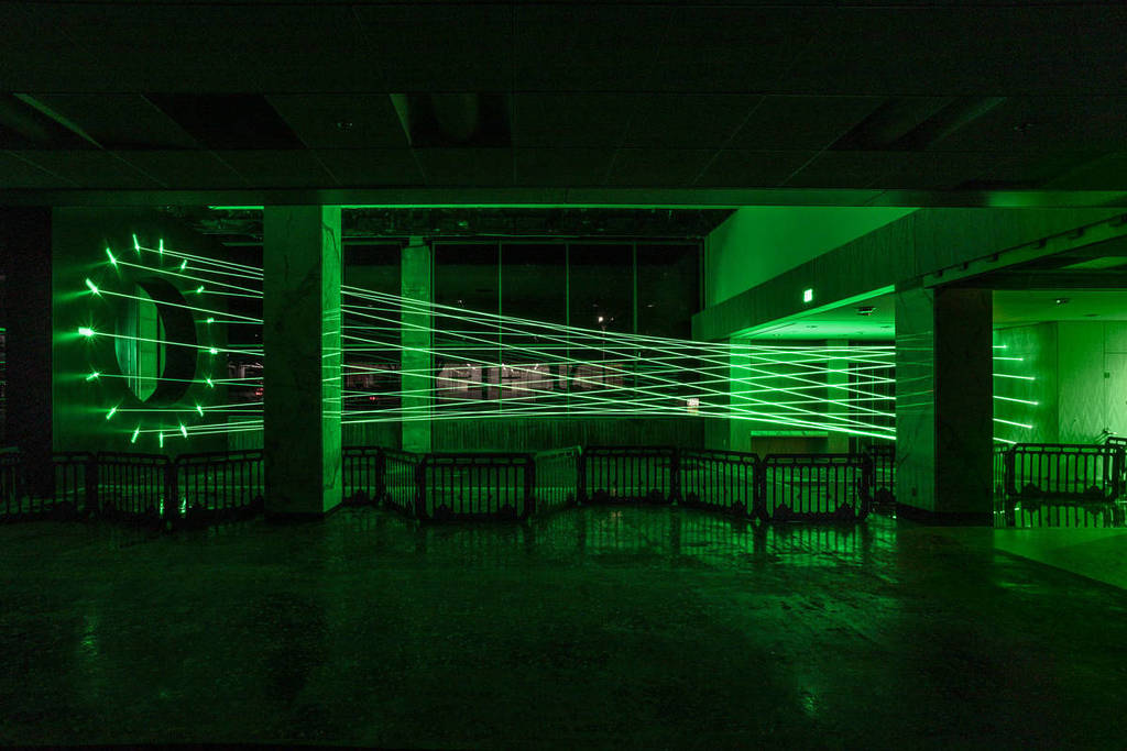 A web-shaped projection of green lasers in a dark room